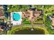 Aerial view of community clubhouse, pool, and pond, surrounded by mature trees and lush landscaping at 9416 Lake Chase Island Way # 9416, Tampa, FL 33626