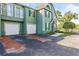 Exterior view of a two-story green townhouse with a two-car garage and manicured landscaping at 9416 Lake Chase Island Way # 9416, Tampa, FL 33626