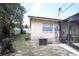 Backyard with window views, AC unit, tree stump, partial fence, and limited yard space at 11411 N 19Th St, Tampa, FL 33612
