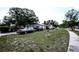 Home's front yard with a lawn, a driveway, several parked vehicles, and mature trees at 11411 N 19Th St, Tampa, FL 33612