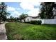 Home's front yard featuring a lawn, a walkway, lush shrubbery, and a partial privacy fence at 11411 N 19Th St, Tampa, FL 33612