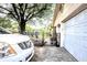 View of a two-car garage with a white vehicle parked beside the black metal fence and a large tree in the front yard at 11411 N 19Th St, Tampa, FL 33612