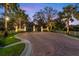 Elegant gated entrance with brick driveway, manicured landscaping, and soft lighting at 11441 Hammock Oaks Ct, Lithia, FL 33547