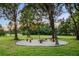 Scenic fire pit area with gravel base, stump seating, and overhead string lights for cozy outdoor gatherings at 11441 Hammock Oaks Ct, Lithia, FL 33547