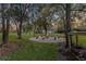 Backyard area featuring a fire pit surrounded by mature trees and green grass at 11441 Hammock Oaks Ct, Lithia, FL 33547