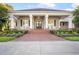 Welcoming front entrance with brick walkway, rocking chairs, and a charming porch with large white columns at 11441 Hammock Oaks Ct, Lithia, FL 33547