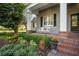 Charming front porch featuring a swing, brick steps, and lush landscaping at 11441 Hammock Oaks Ct, Lithia, FL 33547