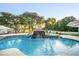 Gorgeous backyard pool with waterfall feature, sun loungers, a poolside dining area, and professional landscaping at 11441 Hammock Oaks Ct, Lithia, FL 33547