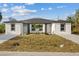 Charming duplex featuring a well-manicured lawn and freshly painted white facade under a cloudy blue sky at 12231 Kirk Ave, Port Charlotte, FL 33981