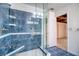 Spacious glass-enclosed shower with blue tiling and convenient built-in seating and shelves at 128 1St Street E. # 102, Tierra Verde, FL 33715