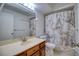 Standard bathroom with a light countertop, wooden cabinet, and bathtub-shower combo with marble pattern curtain at 128 1St Street E. # 102, Tierra Verde, FL 33715