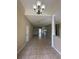 The long, open living room features gorgeous tile floors, a modern chandelier, and a neutral color palette at 13632 Deventer Ct., Hudson, FL 34667
