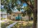 Charming home exterior with a teal front door, covered porch, landscaping and two Adirondack chairs at 1420 W Rambla St, Tampa, FL 33612
