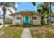 Charming home featuring a vibrant blue front door and two blue chairs on the front porch at 1420 W Rambla St, Tampa, FL 33612