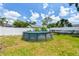 Backyard featuring an above-ground pool with a ladder, partial fencing, landscaping and a lawn at 1420 W Rambla St, Tampa, FL 33612