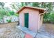 Exterior view of a backyard shed with a green door, surrounded by lush greenery and a chain-link fence at 1512 W Sitka St, Tampa, FL 33604