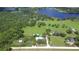 Panoramic aerial view of the property, featuring a home, pool, verdant landscape, and a serene lake backdrop at 16930 Sweetwater Rd, Dade City, FL 33523