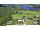Expansive aerial shot showcases the property with a pool, lush greenery, and a picturesque lake at 16930 Sweetwater Rd, Dade City, FL 33523