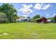 Lush green backyard features a covered patio, charming red barn, and ample open space at 16930 Sweetwater Rd, Dade City, FL 33523