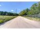 A view of a long dirt road leading to the property surrounded by lush greenery and a wooden fence at 16930 Sweetwater Rd, Dade City, FL 33523
