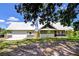 Charming home with light green siding, stone accents, a metal roof, and a detached garage at 16930 Sweetwater Rd, Dade City, FL 33523