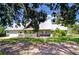 Attractive green home with a modern metal roof, well-kept lawn, and an attached garage at 16930 Sweetwater Rd, Dade City, FL 33523