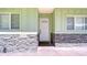 Close-up view of the front door with light green siding and stone accents on the home's facade at 16930 Sweetwater Rd, Dade City, FL 33523