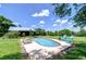Backyard pool features an inviting lounge area, lush green lawn, and sunny skies at 16930 Sweetwater Rd, Dade City, FL 33523