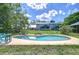 Backyard pool featuring lounge seating, brick trim, and a spacious lawn at 16930 Sweetwater Rd, Dade City, FL 33523