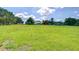 Expansive green field leads up to a quaint home and barn under a sunny, partly cloudy sky at 16930 Sweetwater Rd, Dade City, FL 33523