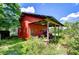Red shed with covered equipment storage and green vegetation around it at 16930 Sweetwater Rd, Dade City, FL 33523
