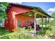 Red shed with covered equipment storage and green vegetation around it at 16930 Sweetwater Rd, Dade City, FL 33523