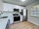 Bright kitchen with stainless steel appliances, stone countertops, white cabinets, and wood-look flooring at 1701 Pinehurst Rd # 16C, Dunedin, FL 34698