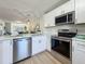 Bright kitchen features stainless appliances, stone countertops, white cabinets, and view to living area at 1701 Pinehurst Rd # 16C, Dunedin, FL 34698