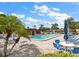 Relaxing pool area with lounge chairs, umbrellas, palm trees, and tables at 1701 Pinehurst Rd # 16C, Dunedin, FL 34698
