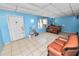 View of living room with tile floors, blue walls, vintage seating, and front door at 2504 Jim Johnson Rd, Plant City, FL 33566