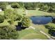 Aerial view of a well-maintained golf course with mature trees and a scenic pond at 3053 Gregor Ct, Palm Harbor, FL 34684