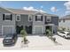 Townhomes feature a neutral gray exterior, a driveway for parking, and simple landscaping for a clean, modern look at 33062 Frosted Clover Way, Wesley Chapel, FL 33545