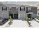 A row of gray townhomes with driveways and minimalistic landscaping featuring palm trees, small bushes, and white gravel at 33062 Frosted Clover Way, Wesley Chapel, FL 33545