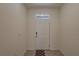 A white front door welcomes guests into the home's entrance, adorned with a window pane for natural light and visibility at 33062 Frosted Clover Way, Wesley Chapel, FL 33545