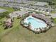 Aerial view of a community pool with ample seating, surrounded by palm trees and landscaping at 33062 Frosted Clover Way, Wesley Chapel, FL 33545