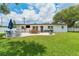 Expansive backyard showcasing a patio area with outdoor seating, lush green grass, and privacy fencing at 3418 W Bay Ave, Tampa, FL 33611