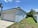 Exterior view of the light blue home featuring an attached two-car garage and a green lawn at 4214 Foxboro Dr, New Port Richey, FL 34653