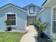 Charming light blue single-Gathering home with a walkway lined by potted palms and decorative rocks at 4214 Foxboro Dr, New Port Richey, FL 34653