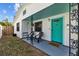 Close-up of a cozy front porch featuring a teal door, seating, and decorative metal supports at 4226 4Th S Ave, St Petersburg, FL 33711