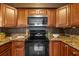 Kitchen featuring a black stove, granite countertops, wood cabinets and stainless steel microwave at 4226 4Th S Ave, St Petersburg, FL 33711