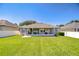 Expansive backyard featuring lush green grass, a screened lanai and white vinyl fencing at 445 Arch Ridge Loop, Seffner, FL 33584