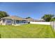 Large grassy backyard featuring a screened-in porch and a white vinyl fence at 445 Arch Ridge Loop, Seffner, FL 33584