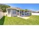 A portion of the backyard shows green grass and a screened-in patio with outdoor furniture at 445 Arch Ridge Loop, Seffner, FL 33584