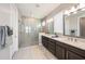 Bright bathroom with double vanity, large mirrors, and glass enclosed shower with a rainfall shower head at 4652 San Martino Dr, Wesley Chapel, FL 33543
